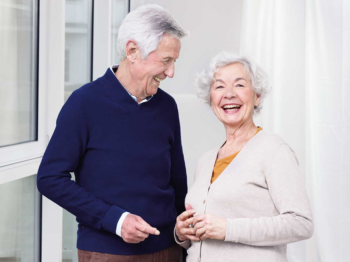En äldre man och äldre kvinna som står tillsammans leende